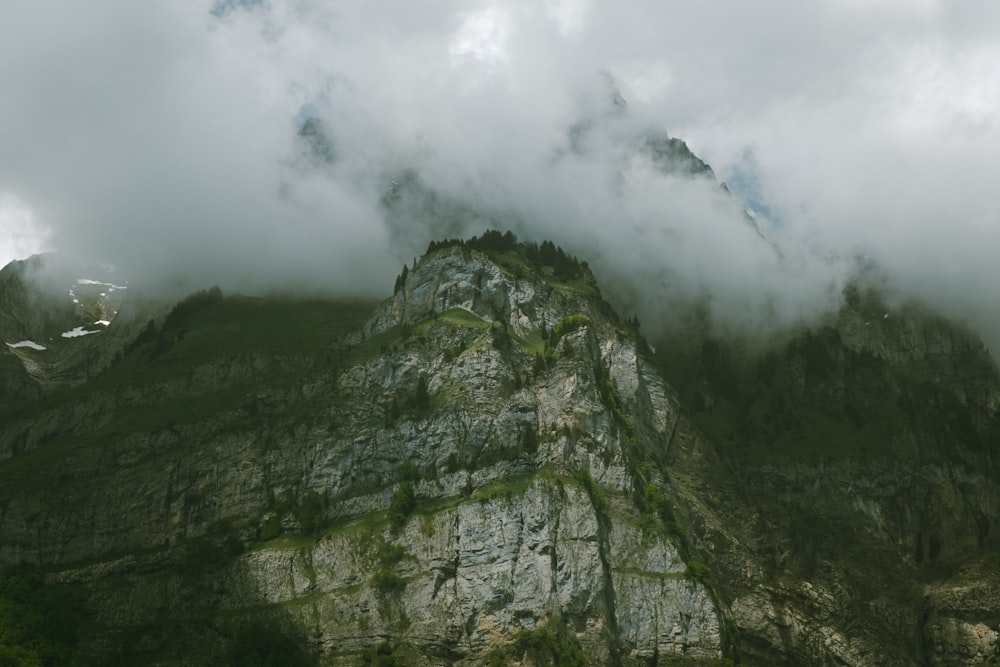 a very tall mountain covered in clouds and trees