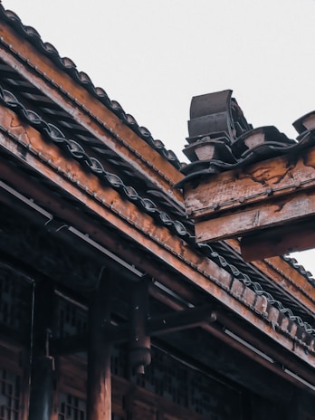 Artisan shaping a teak roof truss with careful attention to detail.
