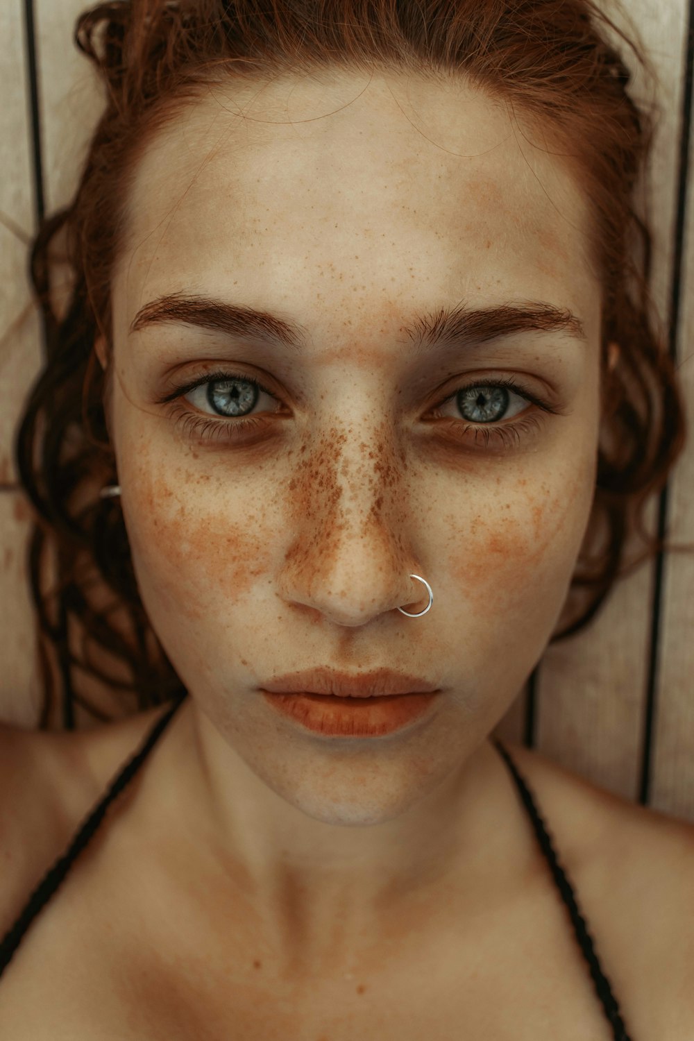 a woman with freckles and a nose piercing