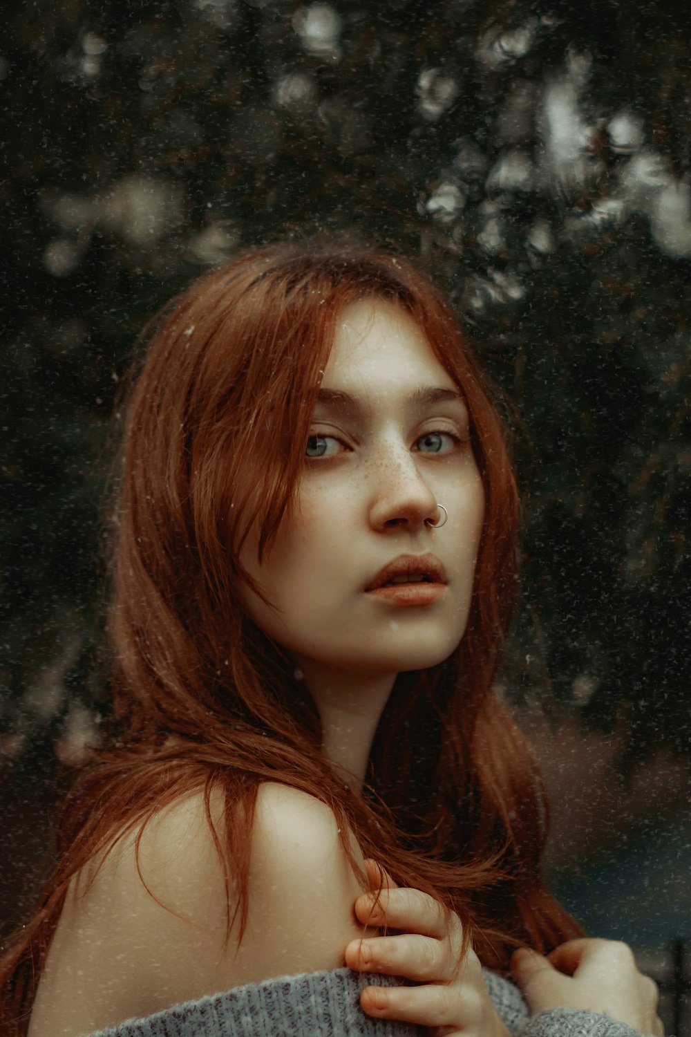 a woman with long red hair standing in front of a tree