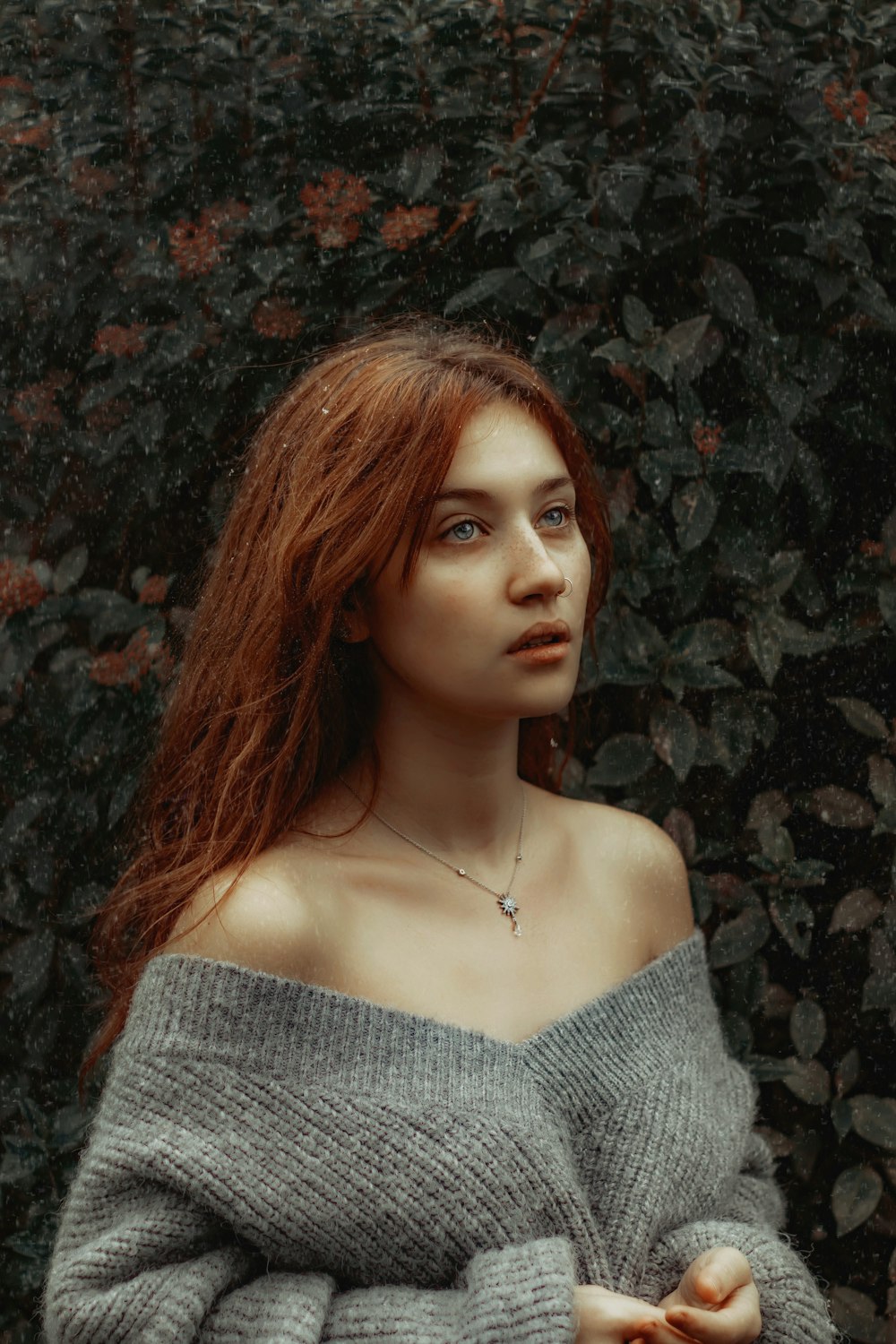 a woman with red hair wearing a gray sweater