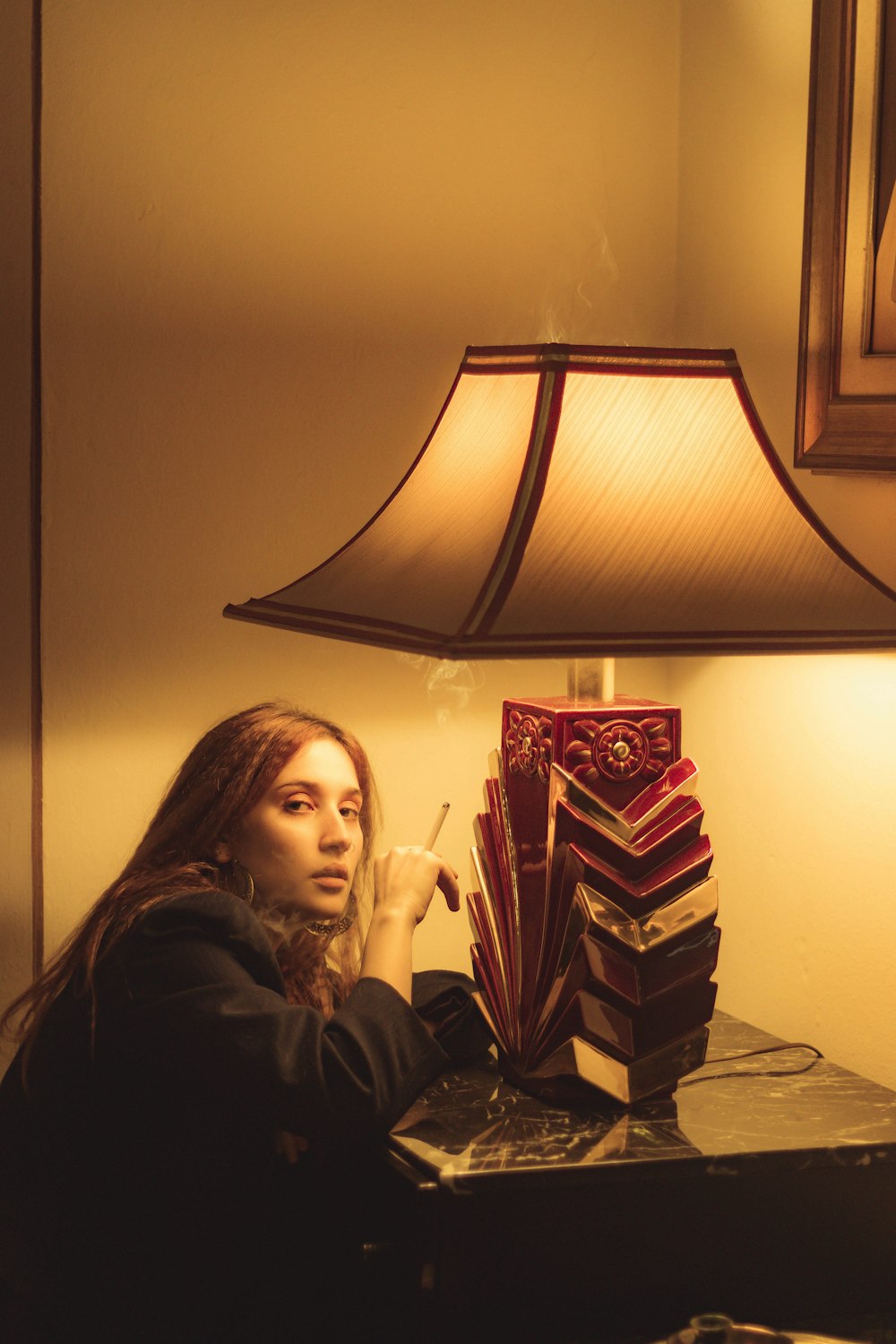 a woman sitting at a table with a lamp on top of it