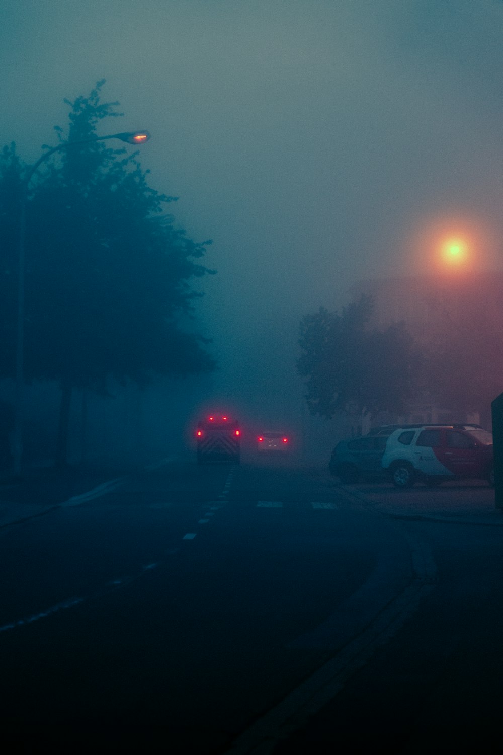 uma rua nebulosa com carros estacionados ao lado da estrada