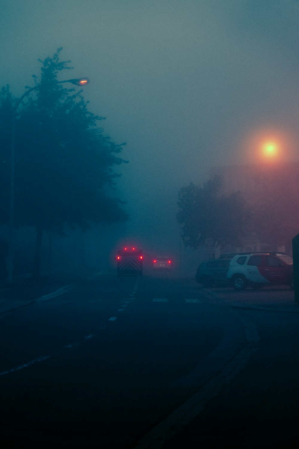 a foggy street with cars parked on the side of the road