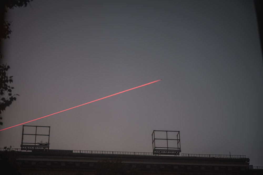 a plane flying over a building with a red streak