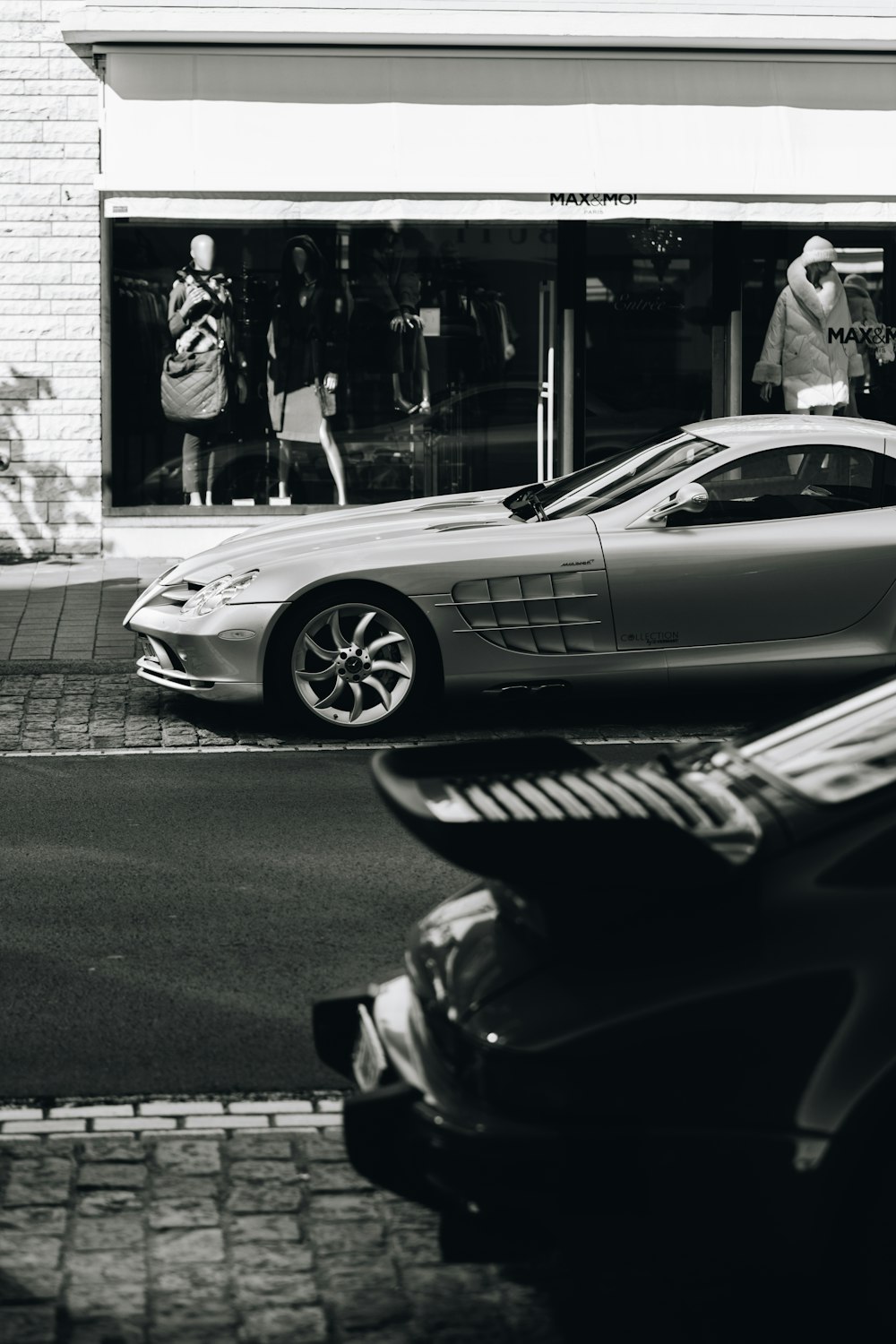 a black and white photo of a car parked in front of a store