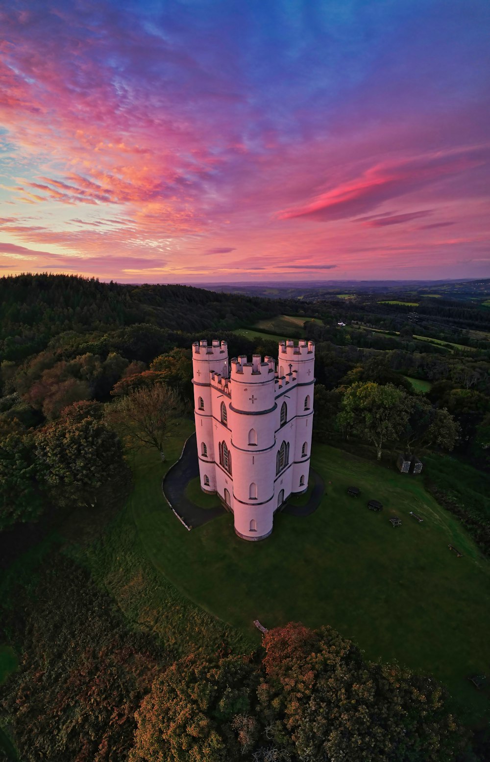 an aerial view of a castle with a sunset in the background