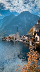 a scenic view of a town on a lake with mountains in the background