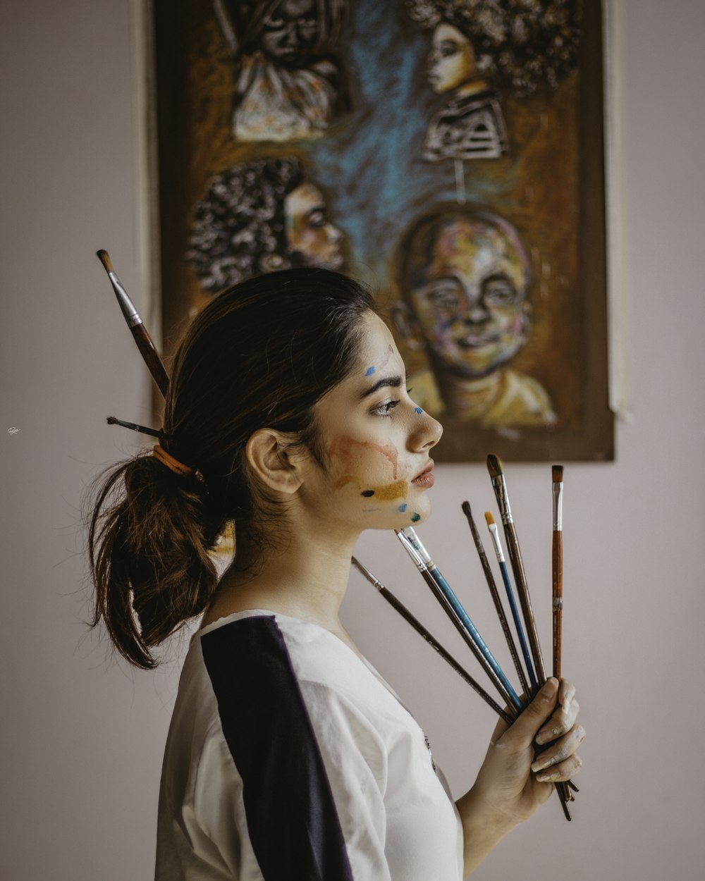 a woman holding a bunch of paint brushes