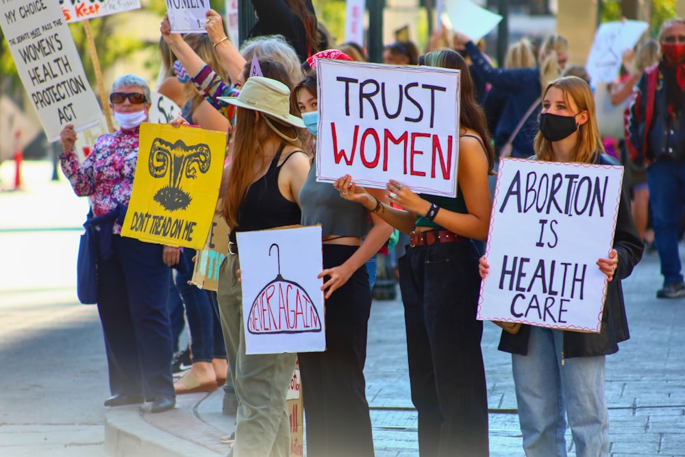 eine Gruppe von Frauen, die Schilder halten und Masken tragen