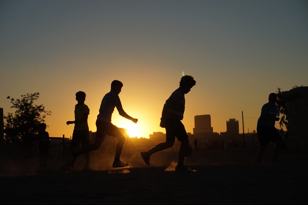 a group of people running across a field at sunset