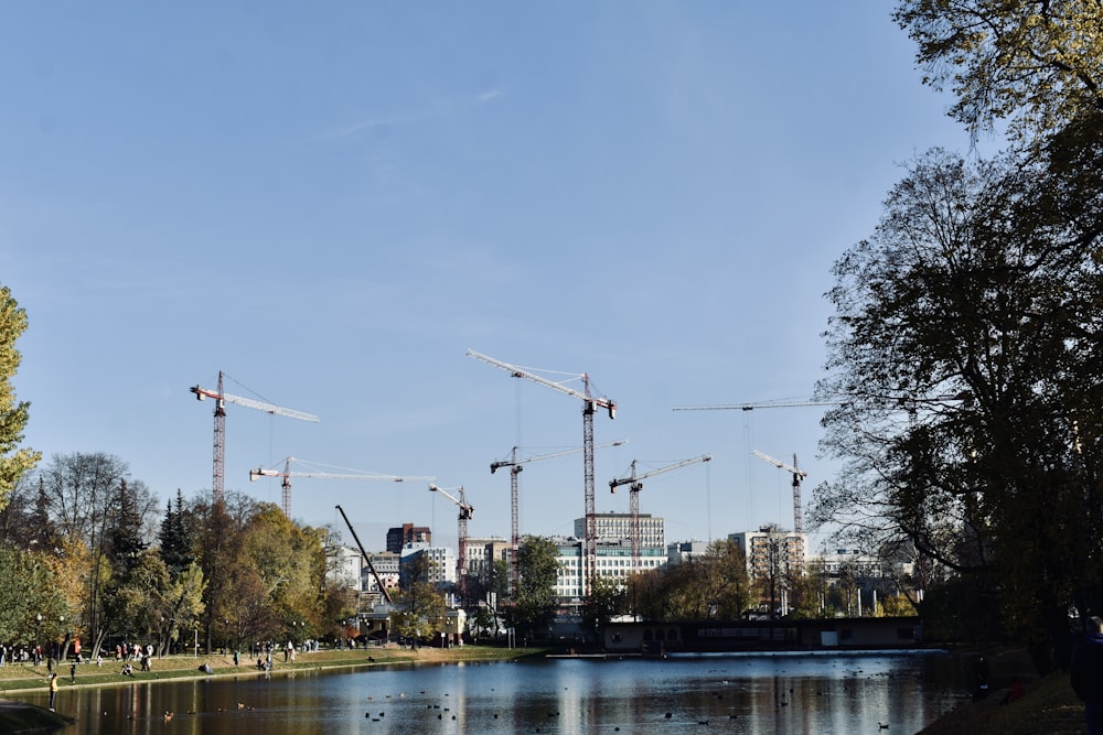 a body of water with cranes in the background