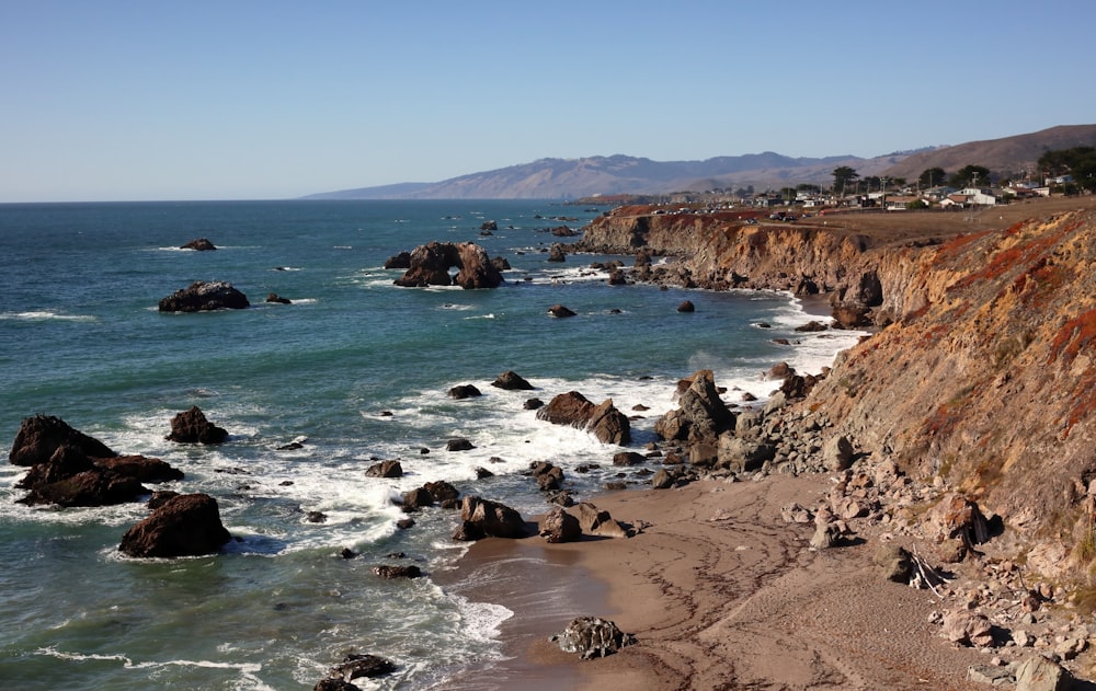 a view of a rocky beach with waves crashing on the shore