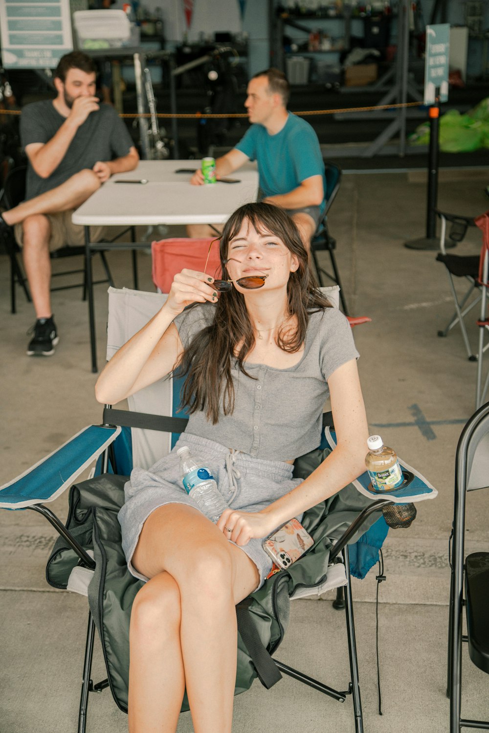 a woman sitting in a chair drinking from a bottle