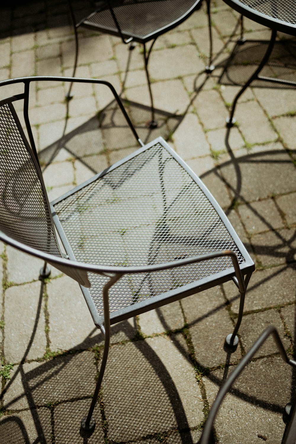 a couple of metal chairs sitting on top of a sidewalk