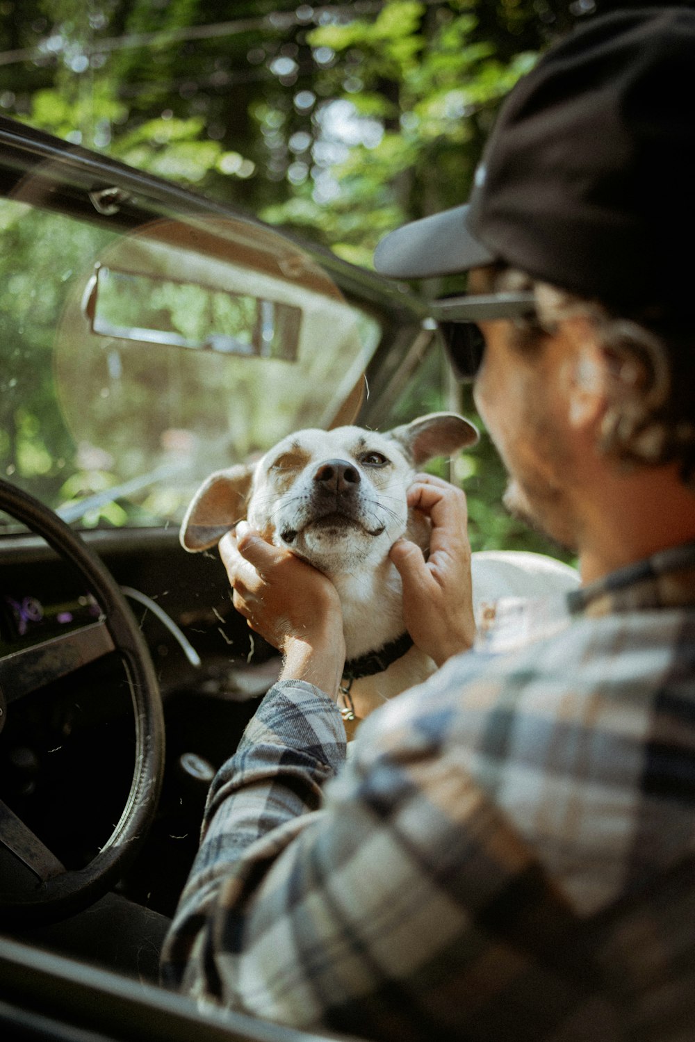 a man driving a car with a dog in his lap