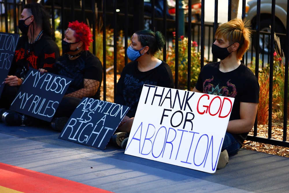 a group of people sitting next to each other holding signs