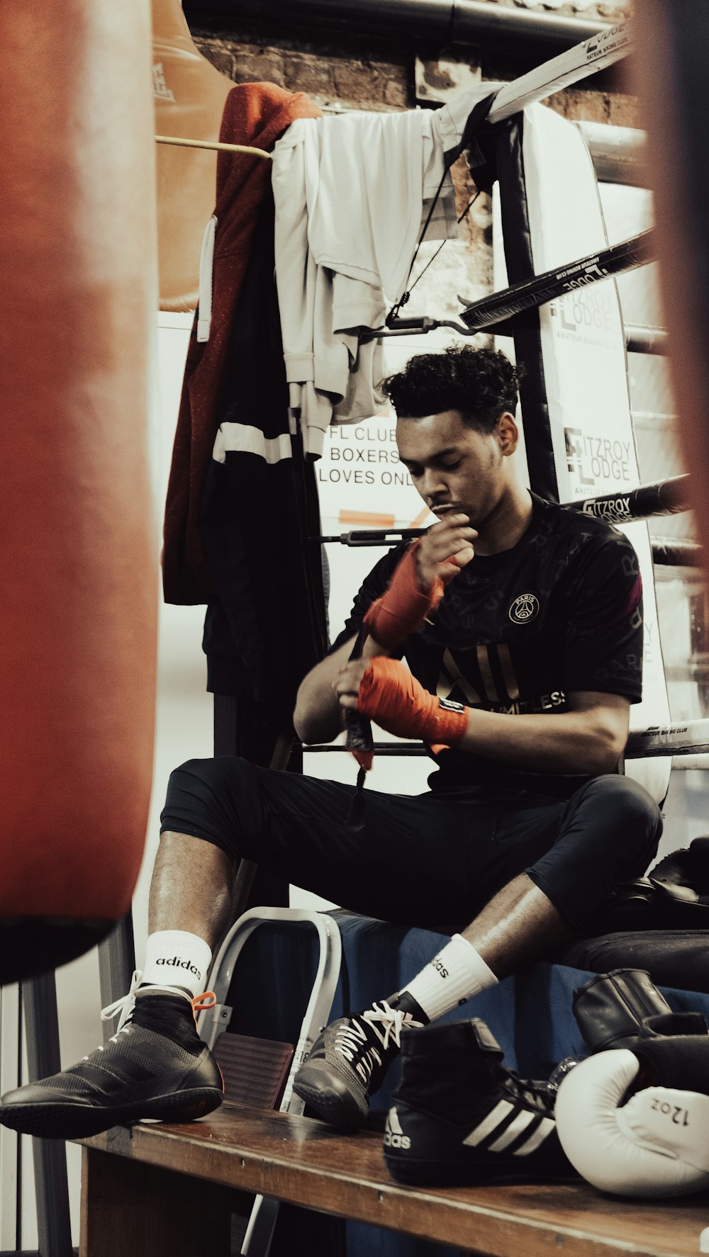 a man sitting on top of a wooden table next to a punching bag