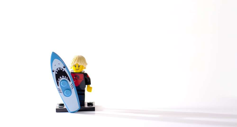 a lego man holding a surfboard on a white background