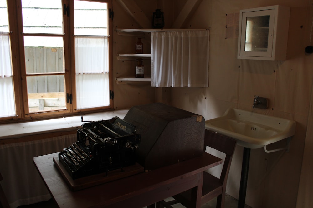 an old fashioned typewriter sitting on a table in front of a window