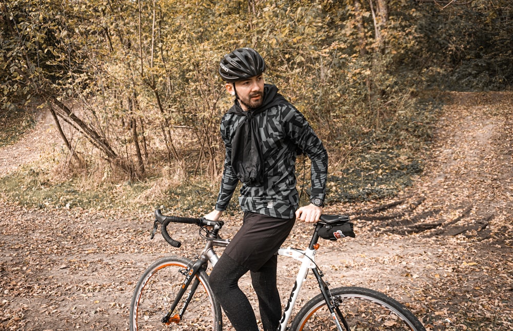 a man standing next to a bike on a dirt road