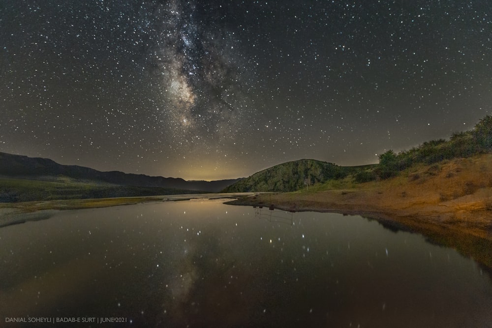 the night sky is filled with stars above a lake