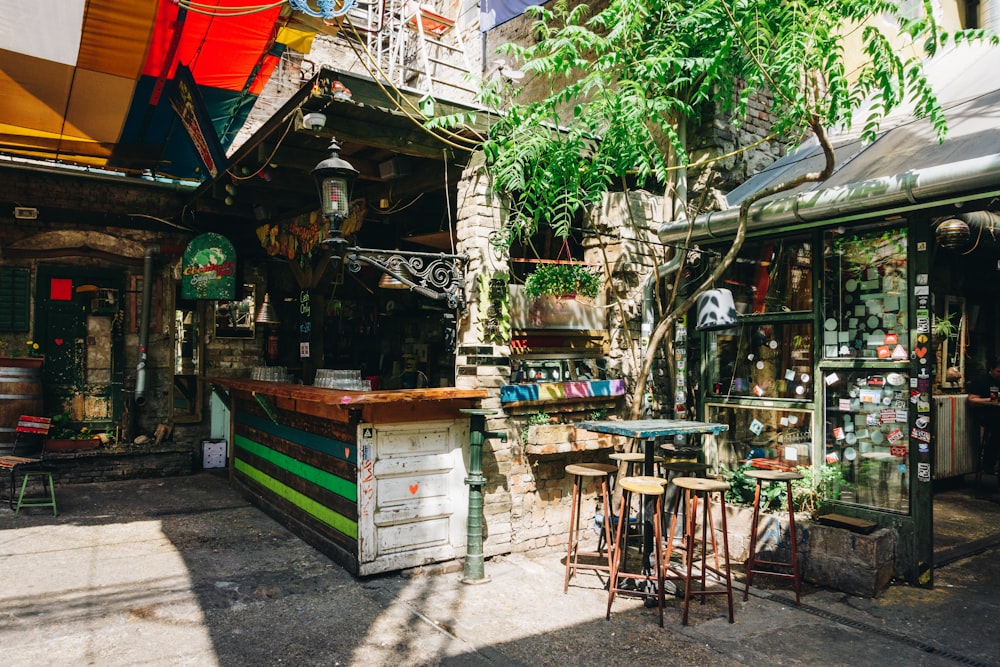 an outdoor cafe with tables and stools in front of it