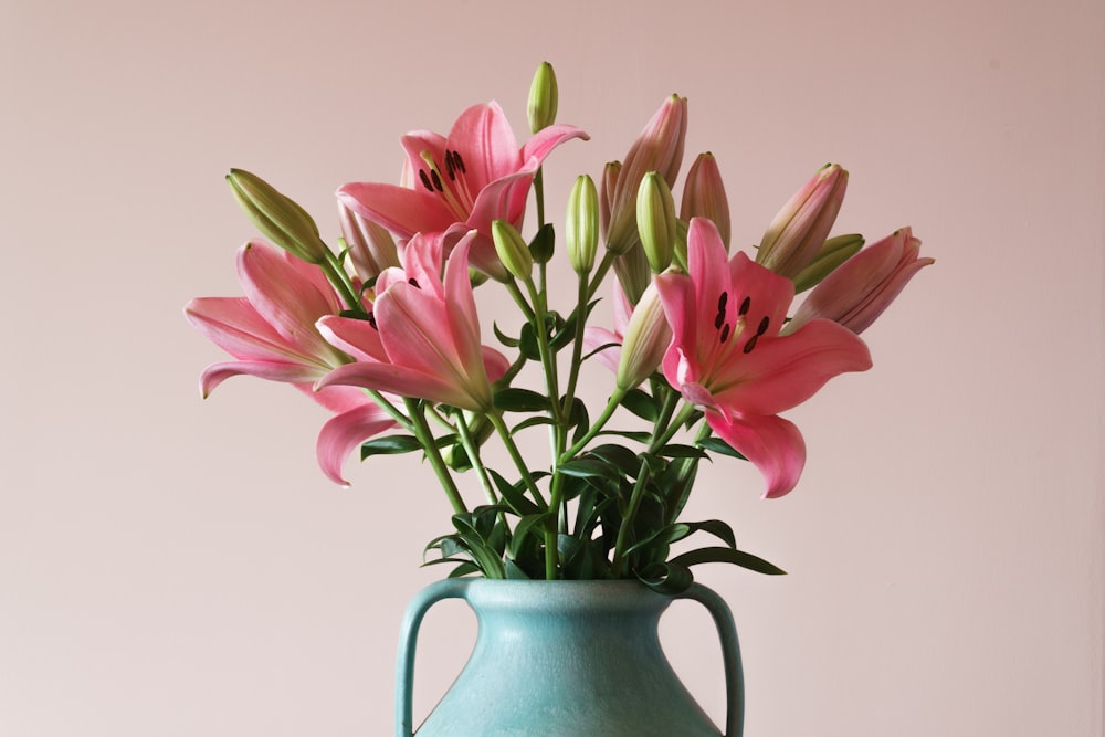 a blue vase filled with pink flowers on top of a table