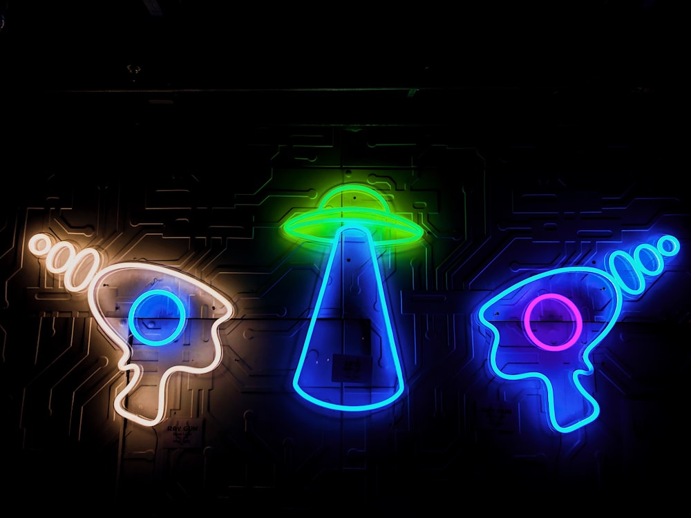 three neon signs that are on a wall