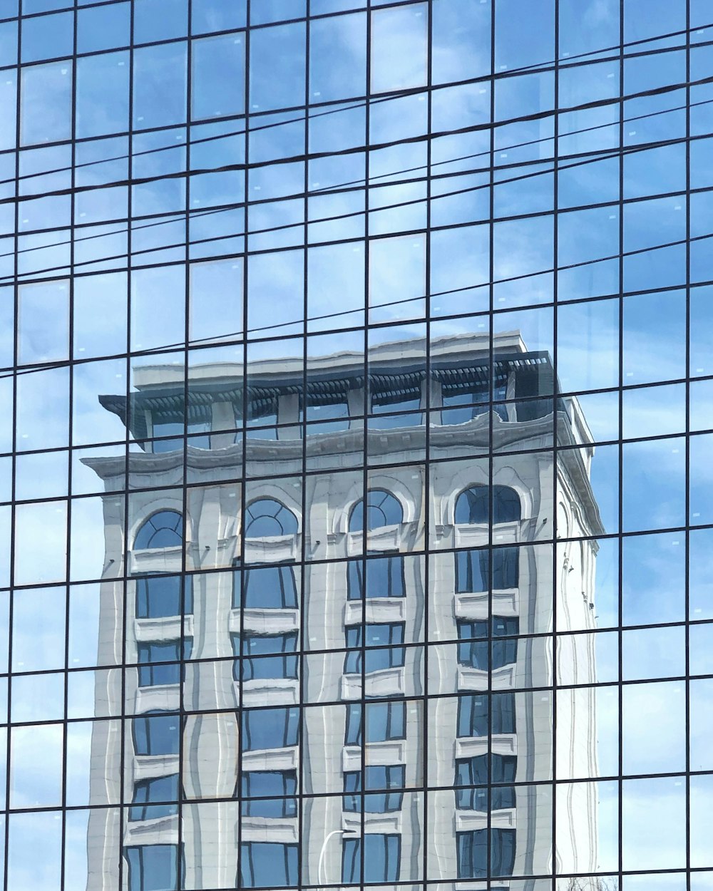 a building is reflected in the windows of another building