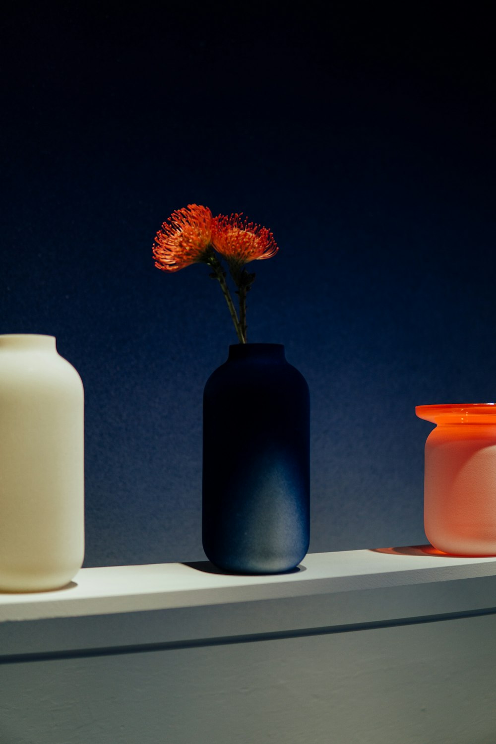 three vases are lined up on a shelf