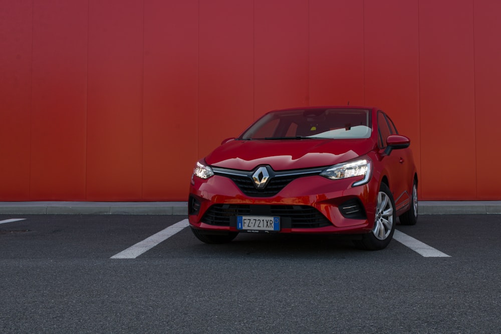 a red car parked in front of a red wall