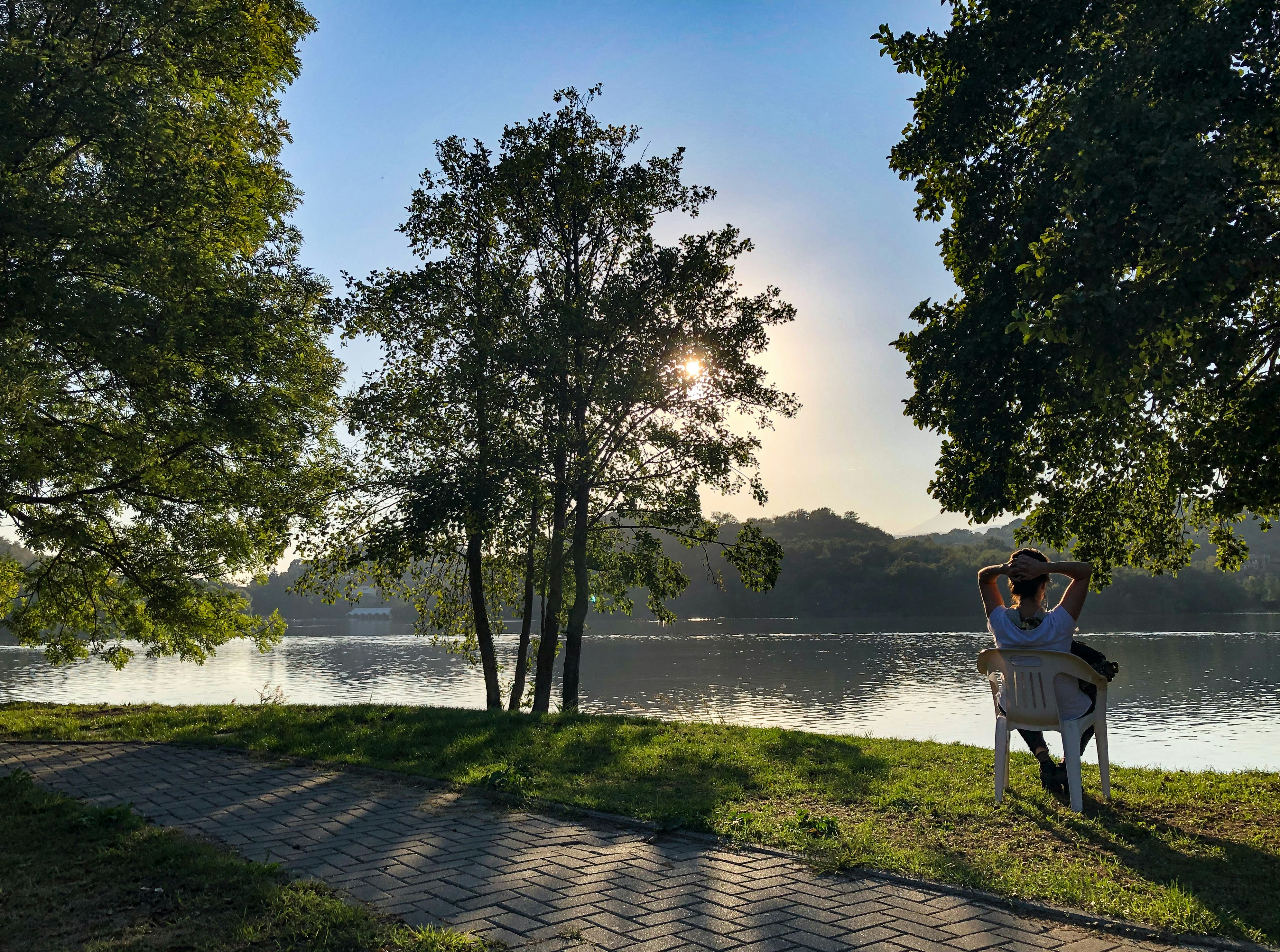 A woman sitting on a bench next to a lake photo – Free Forest Image on ...