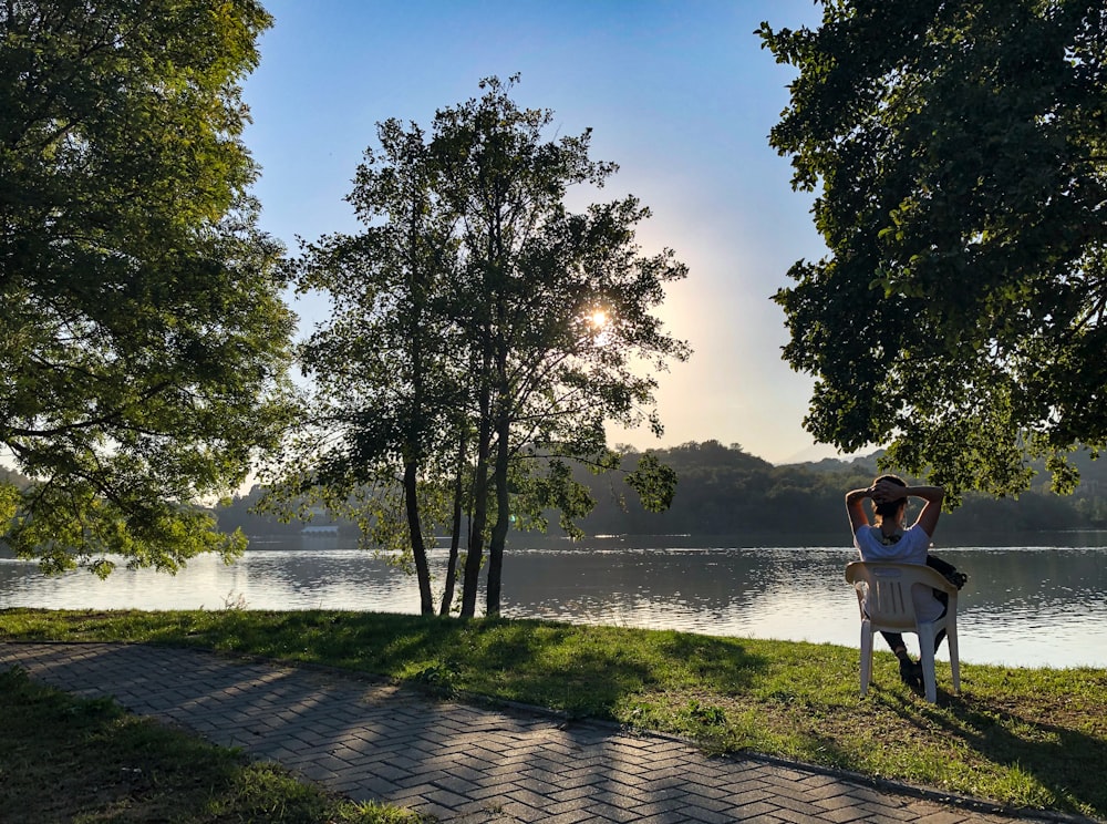 a woman sitting on a bench next to a lake