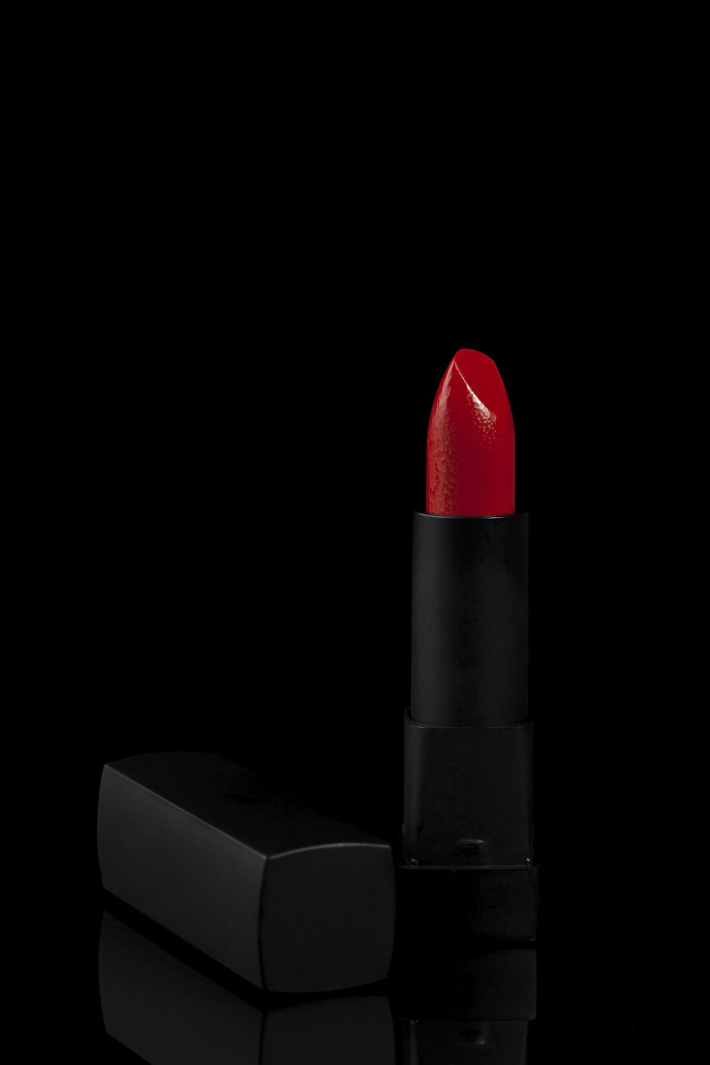 a red lipstick sitting on top of a black surface