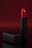 A vibrant red lipstick stands upright against a deep, red backdrop. The lipstick is partially extended from a sleek, black matte tube and is accompanied by a matching cap that lies horizontally beside it. The overall composition is elegant with a focus on the glossy texture of the lipstick.