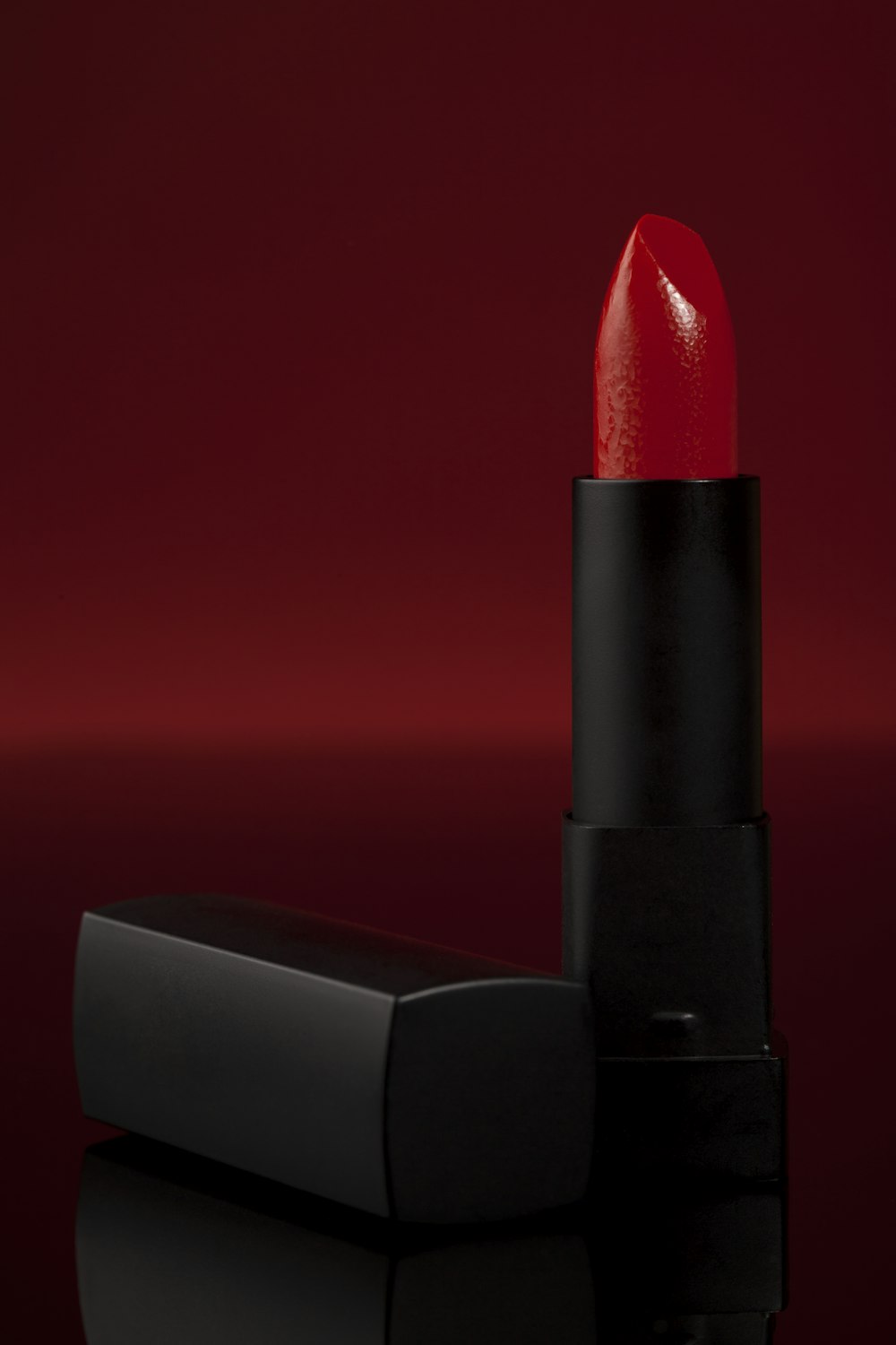 a red lipstick sitting on top of a black table