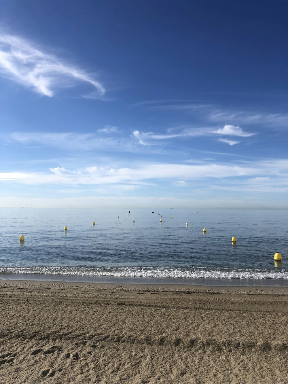 a beach with a bunch of yellow buoys in the water
