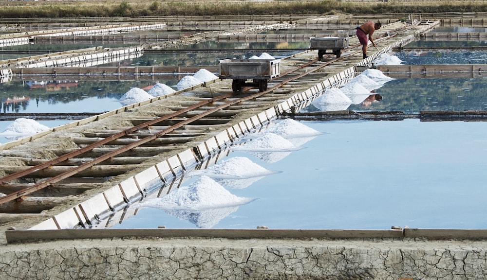 a man standing on a train track next to a large pool of water