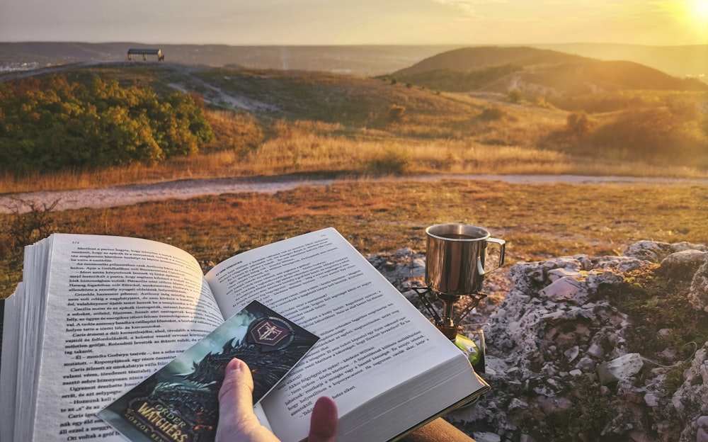 a person is reading a book while sitting on a bench