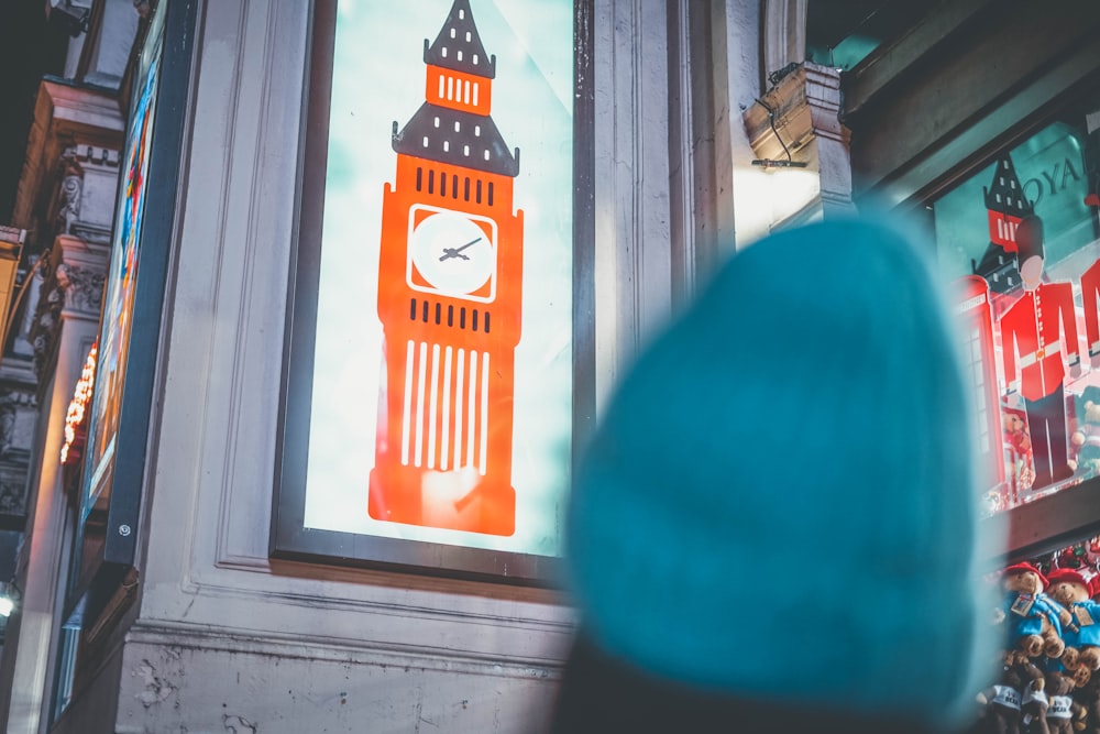 une personne debout devant un bâtiment avec une horloge dessus
