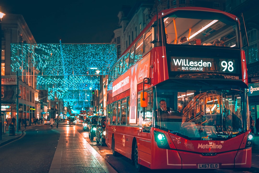 a red double decker bus driving down a street, The streets of London at Christmas.