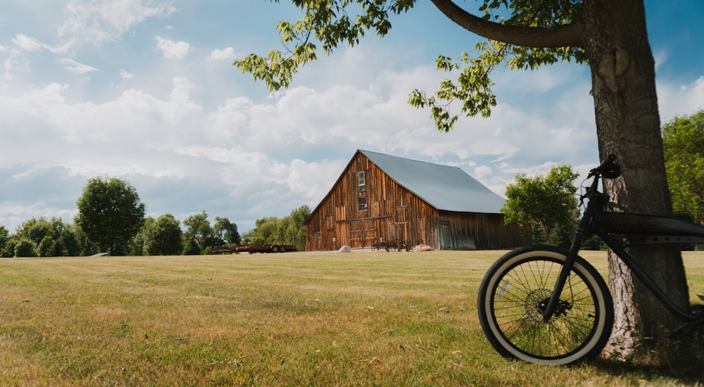 a bike parked next to a tree in a field