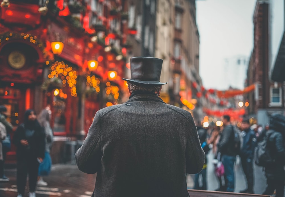 Un uomo con un cappello a cilindro e cappotto che cammina lungo una strada