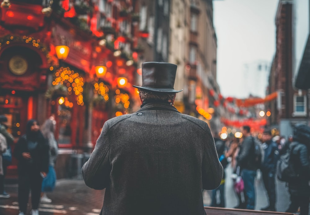 a man in a top hat and coat walking down a street