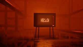 A retro television set displaying the word 'HELLO!' stands in a dimly lit, orange-hued environment. The room has an industrial feel with metal railings on either side, creating a symmetrical perspective leading to the TV.