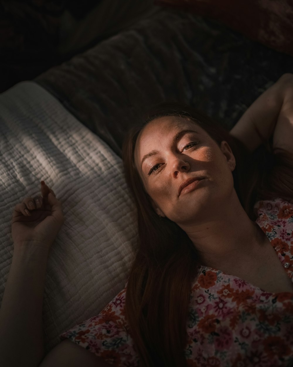 a woman laying on top of a bed next to a pillow