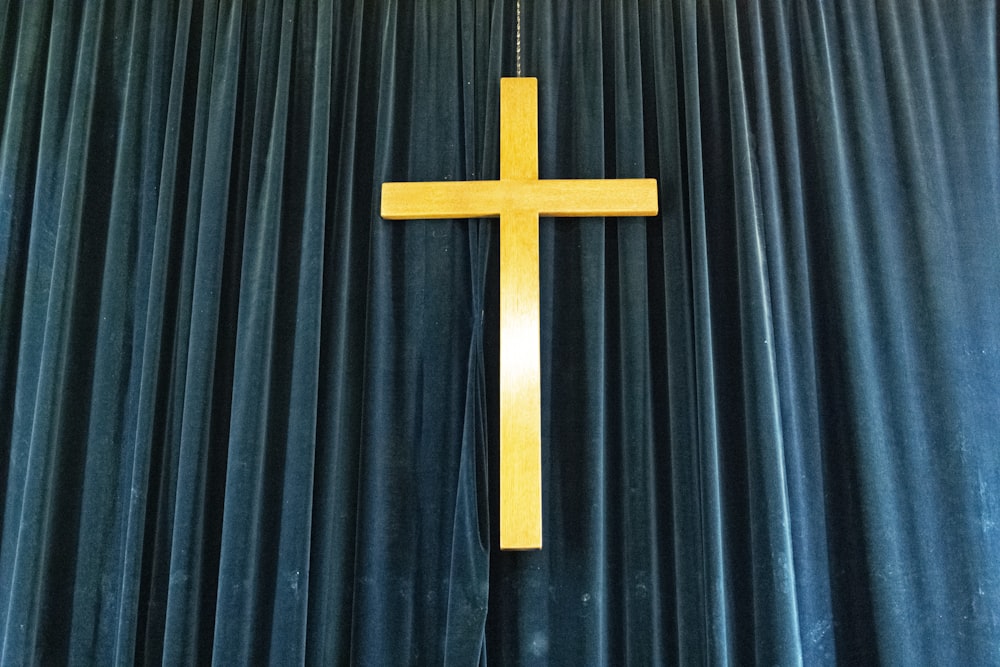 uma cruz pendurada do lado de uma cortina