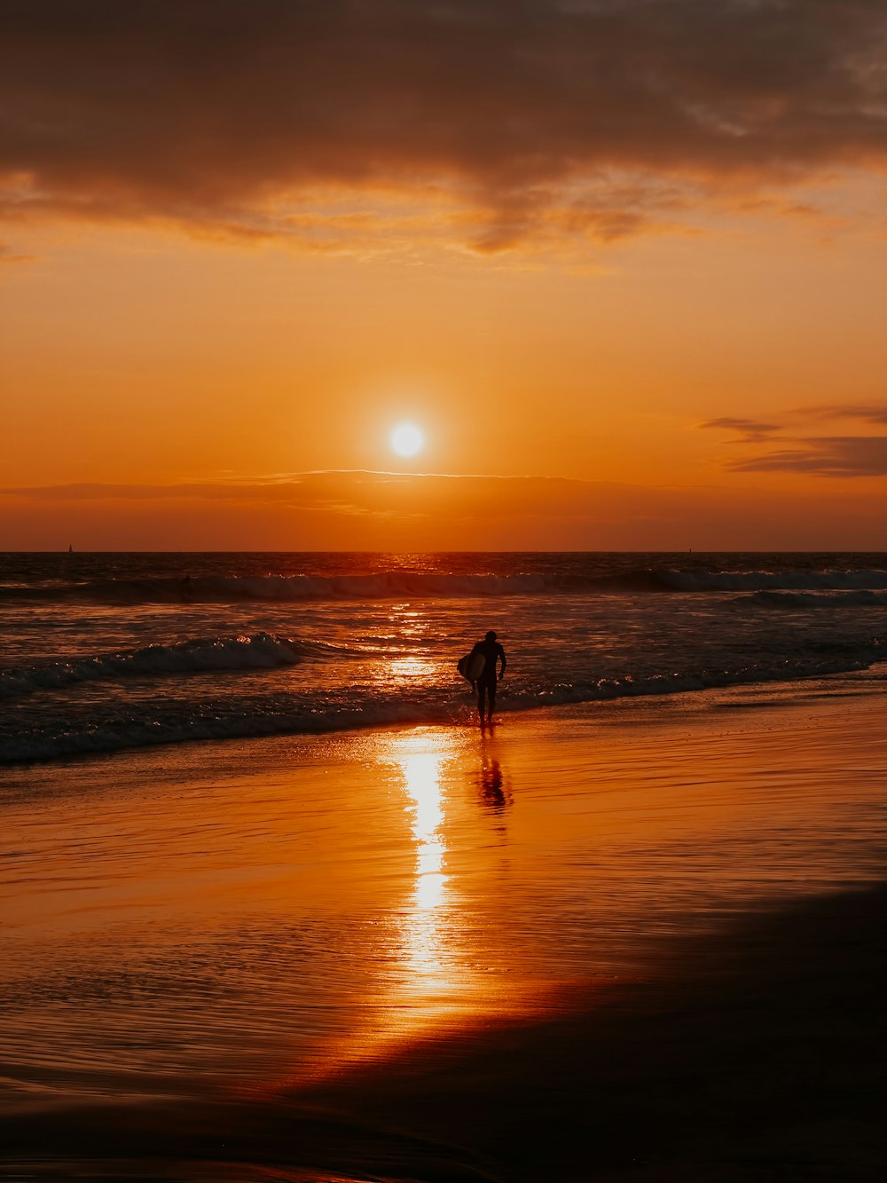 a person walking on the beach at sunset