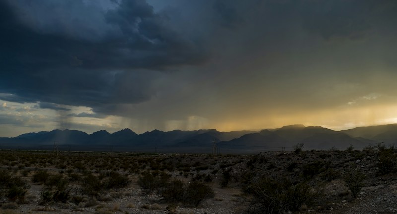 A storm rolls in over the desert with mountains in the background, similar to the storms that reach the Las Vegas Valley